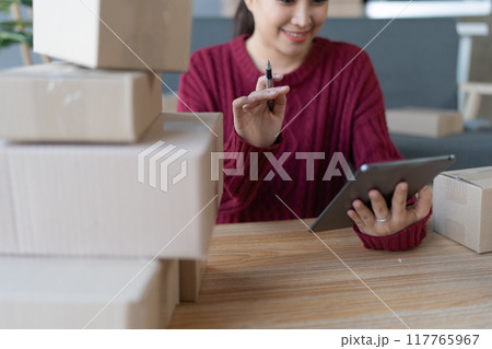 woman, online seller, using a tablet computer efficiently manages customer orders and delivery through the e-commerce platform 117765967