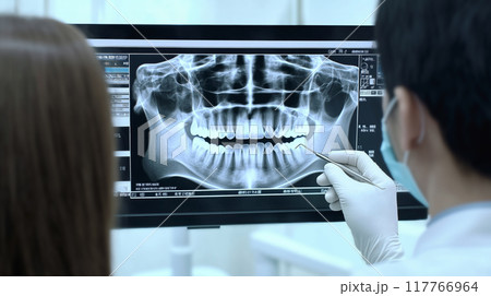 男性の歯科医師が患者に歯のレントゲンを使用するリアルなシーン. 117766964