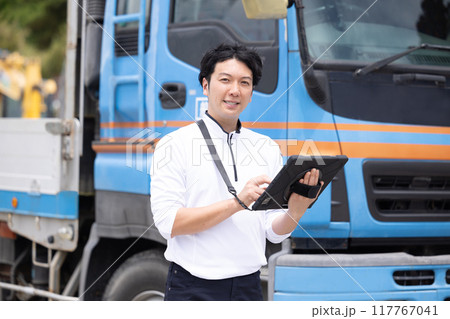 タブレットを持ってトラックの前に立つドライバー 117767041