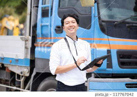 タブレットを持ってトラックの前に立つドライバー 117767042