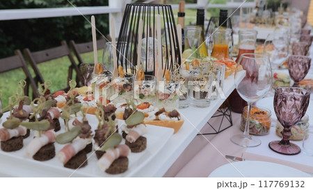 Buffet and snacks at a business event. Beautifully decorated banquet table with appetizers from canapes. Business lunch. Beautiful festive table with appetizers Buffet and snacks at a business event. Beautifully decorated banquet table with appetizers from canapes. Business lunch. Beautiful festive table with appetizers 117769132
