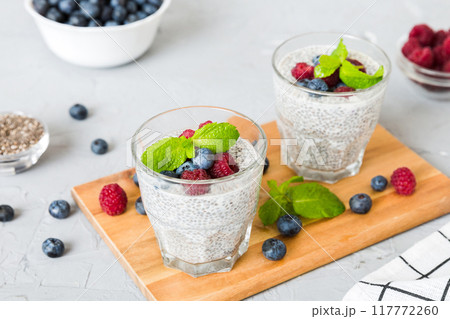 Healthy breakfast or morning with chia seeds vanilla pudding raspberry and blueberry berries on table background, vegetarian food, diet and health concept. Chia pudding with raspberry and blueberry Healthy breakfast or morning with chia seeds vanilla pudding raspberry and blueberry berries on table background, vegetarian food, diet and health concept. Chia pudding with raspberry and blueberry 117772260