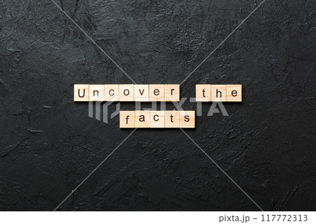 uncover the fact word written on wood block. uncover the fact text on table, concept 117772313