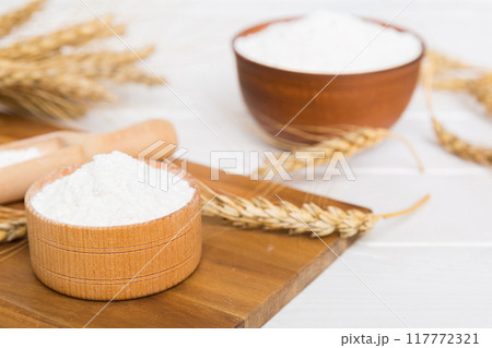 Flat lay of Wheat flour in wooden bowl with wheat spikelets on colored background. world wheat crisis 117772321