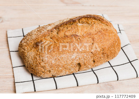 freshly baked bread with napkin on rustic table top view. Healthy white bread loaf isolated 117772409