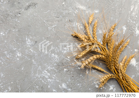 Sheaf of wheat ears close up and seeds on colored background. Natural cereal plant, harvest time concept. Top view, flat lay with copy space. world wheat crisis Sheaf of wheat ears close up and seeds on colored background. Natural cereal plant, harvest time concept. Top view, flat lay with copy space. world wheat crisis 117772970