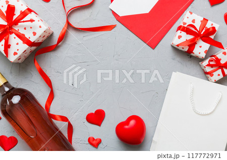 top view photo of st valentine day decor shopping, bag, wine, bottle, envelope, gift, box, candy and red heart on colored background with empty space. Frame background top view photo of st valentine day decor shopping, bag, wine, bottle, envelope, gift, box, candy and red heart on colored background with empty space. Frame background 117772971