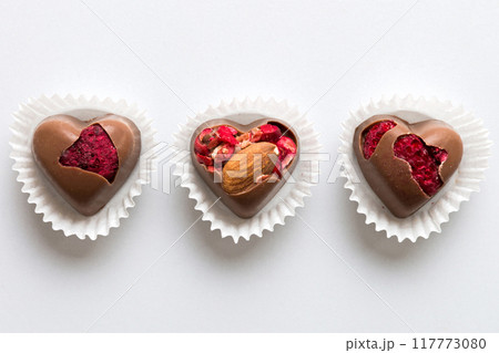 chocolate sweets in the form of a heart with fruits and nuts on a colored background. top view with space for text, holiday concept chocolate sweets in the form of a heart with fruits and nuts on a colored background. top view with space for text, holiday concept 117773080