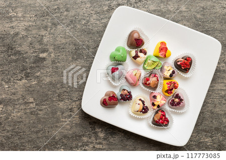 Plate with different chocolate on colored background. Assortment of fine chocolates top view vith copy space Health and obesity concept 117773085