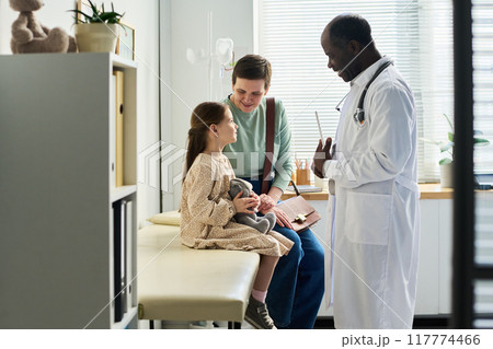 Doctor Conversing with Child and Parent in Clinic Room Doctor Conversing with Child and Parent in Clinic Room 117774466