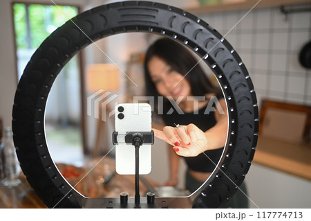 Smiling athletic young woman recording video lesson on smart phone about how to making healthy meal 117774713