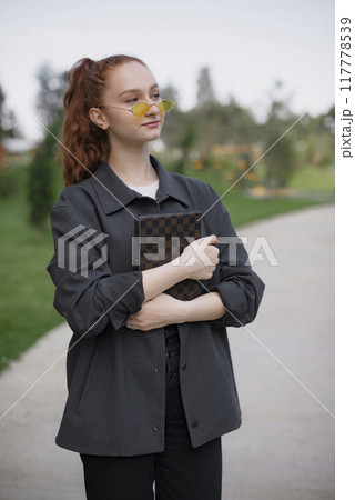 Front view of pretty girl holding notebook with crossed hands, looking forward. Concept of modern lifestyle. 117778539