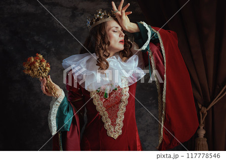 disappointed medieval queen in red dress with dried flower disappointed medieval queen in red dress with dried flower 117778546