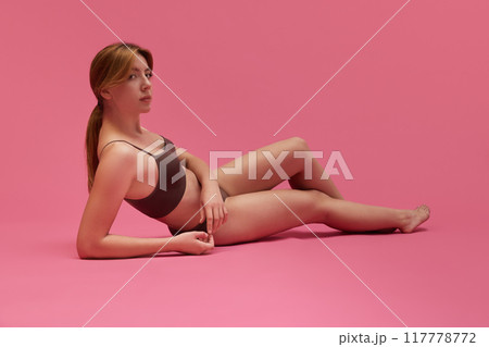 Portrait of attractive young girl with sportive, healthy, skinny body posing in underwear against pink studio background 117778772