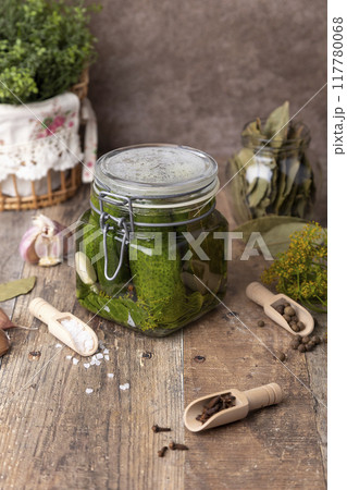 Half-sour dill pickle (quick pickled cucumbers) in a jar with seasonings, spices and herbs. Homemade seasonal preparations. Traditional canning of vegetables. Selective focus, close-up. Half-sour dill pickle (quick pickled cucumbers) in a jar with seasonings, spices and herbs. Homemade seasonal preparations. Traditional canning of vegetables. Selective focus, close-up. 117780068