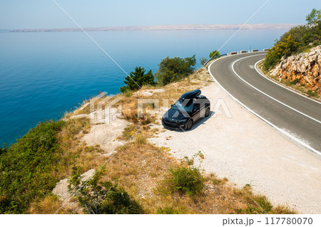 Car with a roof box stands on the side of a cliff and beautiful rocks in the background. Car with a roof box stands on the side of a cliff and beautiful rocks in the background. 117780070
