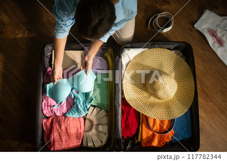 Woman organizing clothes and packing suitcase for trip 117782344