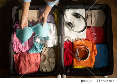 Woman organizing clothes and packing suitcase for trip Woman organizing clothes and packing suitcase for trip 117782467
