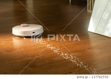 Robot vacuum cleaner removing dirt from wooden floor Robot vacuum cleaner removing dirt from wooden floor 117782550