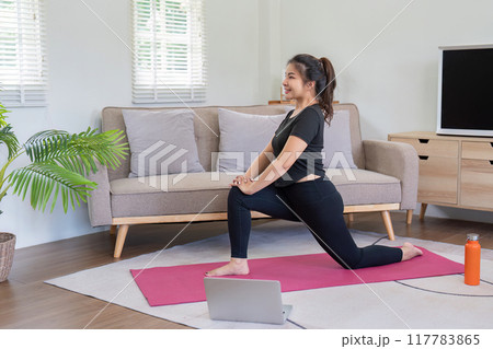 Happy Woman Performing Yoga Poses Guided by Laptop Happy Woman Performing Yoga Poses Guided by Laptop 117783865