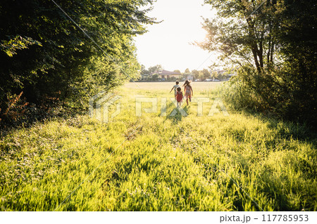 rear view of three children running towards open field rear view of three children running towards open field 117785953