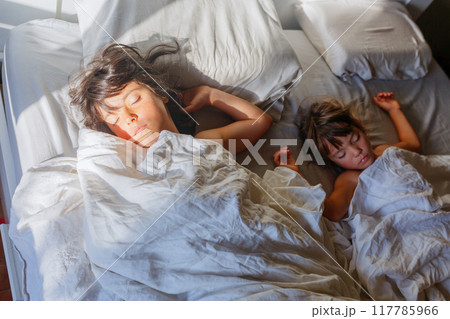 upper view on two little children sleeping on parents bed on sunny morning upper view on two little children sleeping on parents bed on sunny morning 117785966