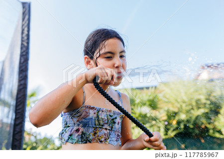 low angle view of child drinking directly from hosepipe on a sunny hot day low angle view of child drinking directly from hosepipe on a sunny hot day 117785967