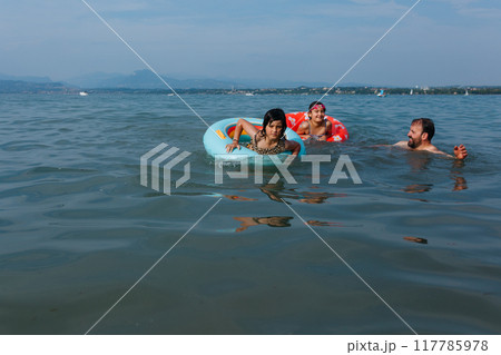 father and two daughters swimming in the lake on sunny day father and two daughters swimming in the lake on sunny day 117785978