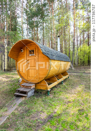 Wooden barrel-shaped sauna in the forest on a sunny day. Vertical photo 117786787