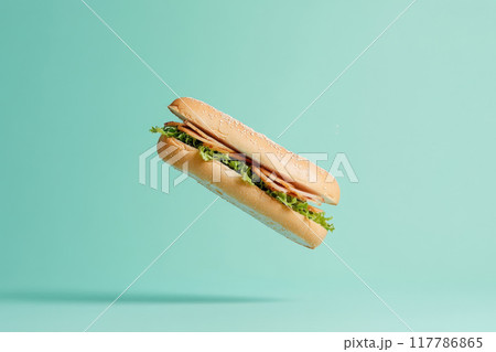Delicious floating sandwich with fresh greens on a vibrant mint background, perfect for food-related projects. 117786865