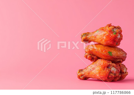 Close up of crispy chicken wings with herbs on pink background 117786866