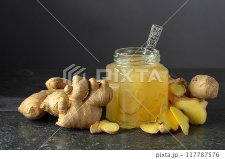 Ginger jam in jar and fresh ginger on a black background. 117787576