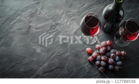 Red wine bottle and glasses arranged on a dark stone surface for a cozy evening gathering 117788538