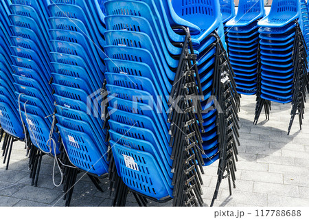 Stacked rows of blue plastic chairs with metal frames for outdoor events on town square 117788688