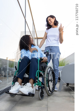 Young woman carrying a wheelchair with a disabled african american woman 117788710