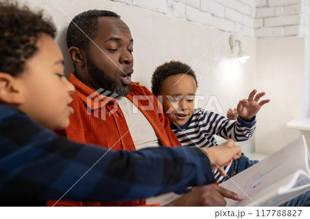 Father and kids reading stories before sleep and looking interested 117788827