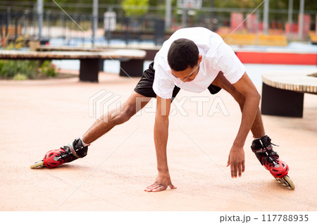 Young man on rollers trying to keep balance and starting to fall down Young man on rollers trying to keep balance and starting to fall down 117788935
