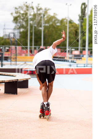 Young man on rollers trying to keep balance and starting to fall down Young man on rollers trying to keep balance and starting to fall down 117788936