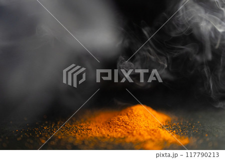 Horizontal picture of pile of red parika with smoke around it.Black background 117790213
