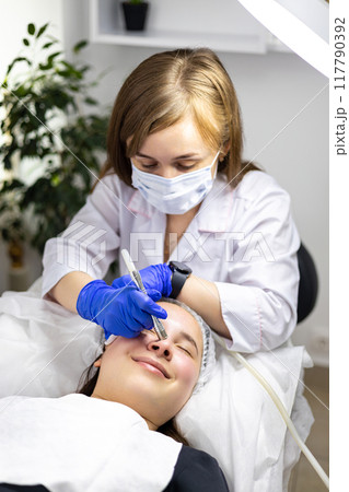 Cosmetologist making procedure microdermabrasion on the face against acne. Medical equipment. Health care, beauty treatment. Skin treatment. Professional 117790392