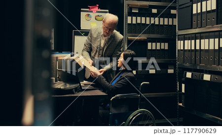 Forensic team extracting DNA samples for modern analysis in archive room, examining criminal evidence and compiles statistical data. Agent with disability working on private investigation. Camera B. 117790629