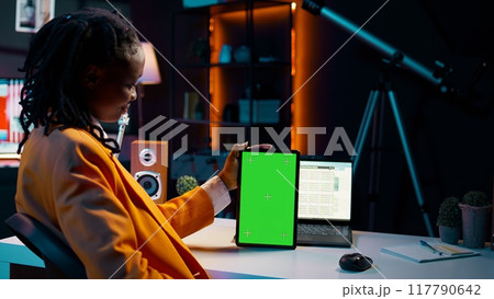 University student looking at greenscreen on tablet learning to use cash plan software, studying business and finances with online classes. Looks at copyspace, conducting data analysis. Camera B. University student looking at greenscreen on tablet learning to use cash plan software, studying business and finances with online classes. Looks at copyspace, conducting data analysis. Camera B. 117790642