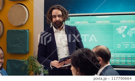 Project manager welcoming his team in business meeting, shaking hands. Supervisor explains the overall enterprise goals, analyzing the current situation and works through planning details. Camera A. 117790664