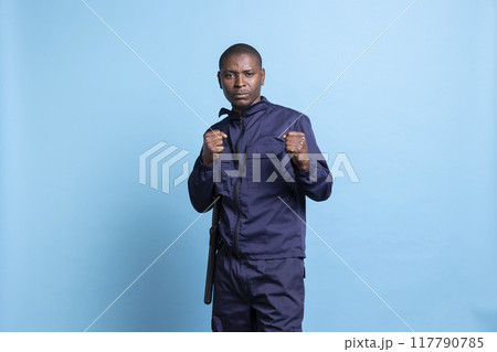 Professional security agent poses with clenched fists in studio, on protection duty ready for a fight in order to safeguard something. Armed guard with proper combat and defense training. Professional security agent poses with clenched fists in studio, on protection duty ready for a fight in order to safeguard something. Armed guard with proper combat and defense training. 117790785