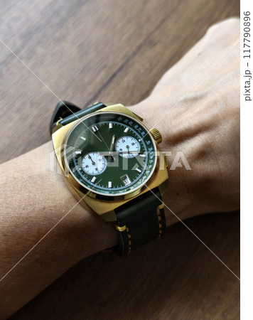 Beautiful luxury golden and green wrist watch on male wrist, 117790896
