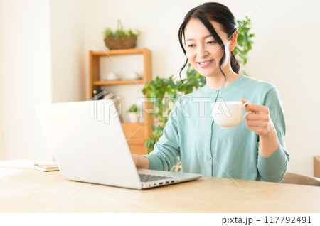 コーヒーを片手にパソコンを操作するミドル女性 117792491