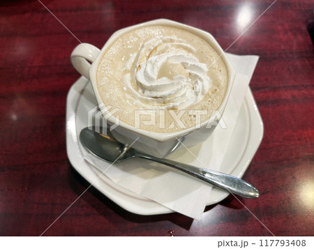cup of cafelatte with spoon on saucer 117793408