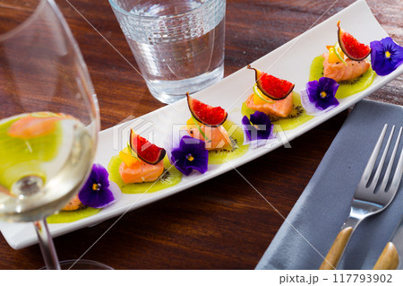Pickled salmon on kiwi with figs, mango, kumquat 117793902