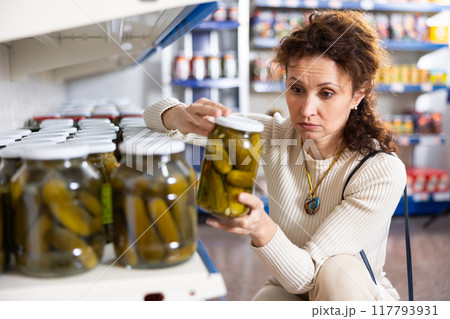 In Russian goods store, woman choose jar of pickled cucumbers In Russian goods store, woman choose jar of pickled cucumbers 117793931