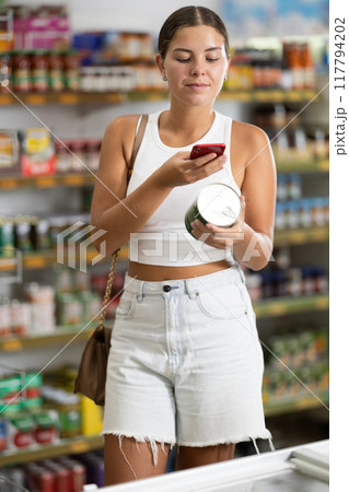 Young woman scanning qr code for canned food Young woman scanning qr code for canned food 117794202